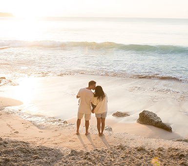 Couple walking together along the shoreline at sunset